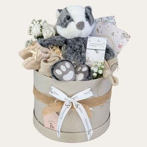 new baby gifts box with a farmyard badger, baby booties, baby hat, baby bib, milestone cards and a bracelet for mum