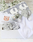 new baby gifts basket with an elephant blanket and elephant soft toy. Chocolates for mum and baby booties in grey.