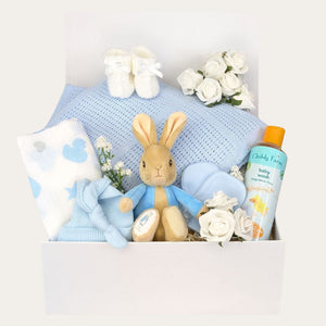 New baby boy gifts hamper in a box packed with  peter rabbit soft toy, blue baby blanket, muslin square, baby hat, baby mittens and booties.