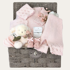 new baby girl gifts hamper basket with pink knit clothing, lamb soft toy, baby booties and a bracelet for mum.