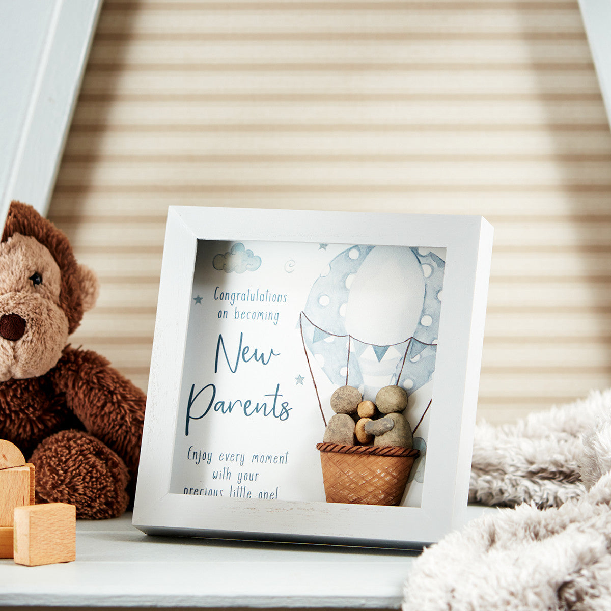 A plaque for new parents featuring two pebble adults and a baby in a hot air balloon with the wording ' Congratulations On becoming new parents. Enjoy every moment with your precious little one 