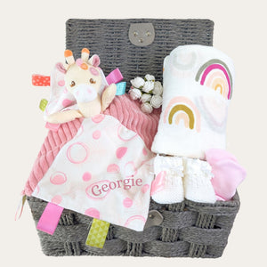 personalised baby girls gifts basket with giraffe comforter, rainbow swaddle, baby booties, baby mittens.