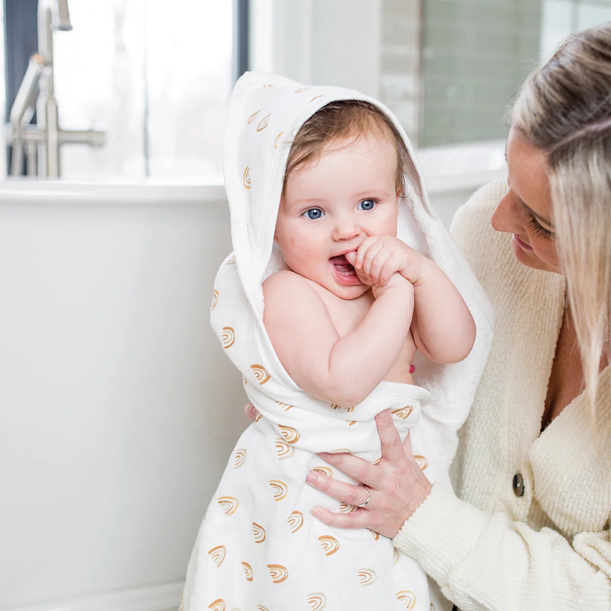 A colourful rainbow hooded towel made with printed muslin and terry cloth, folded and ready for use.