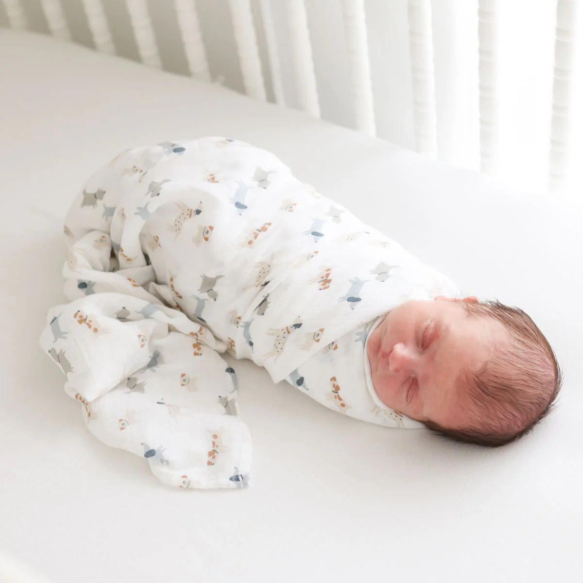 Two cotton muslin baby swaddles with puppy and star designs, folded neatly on a surface.