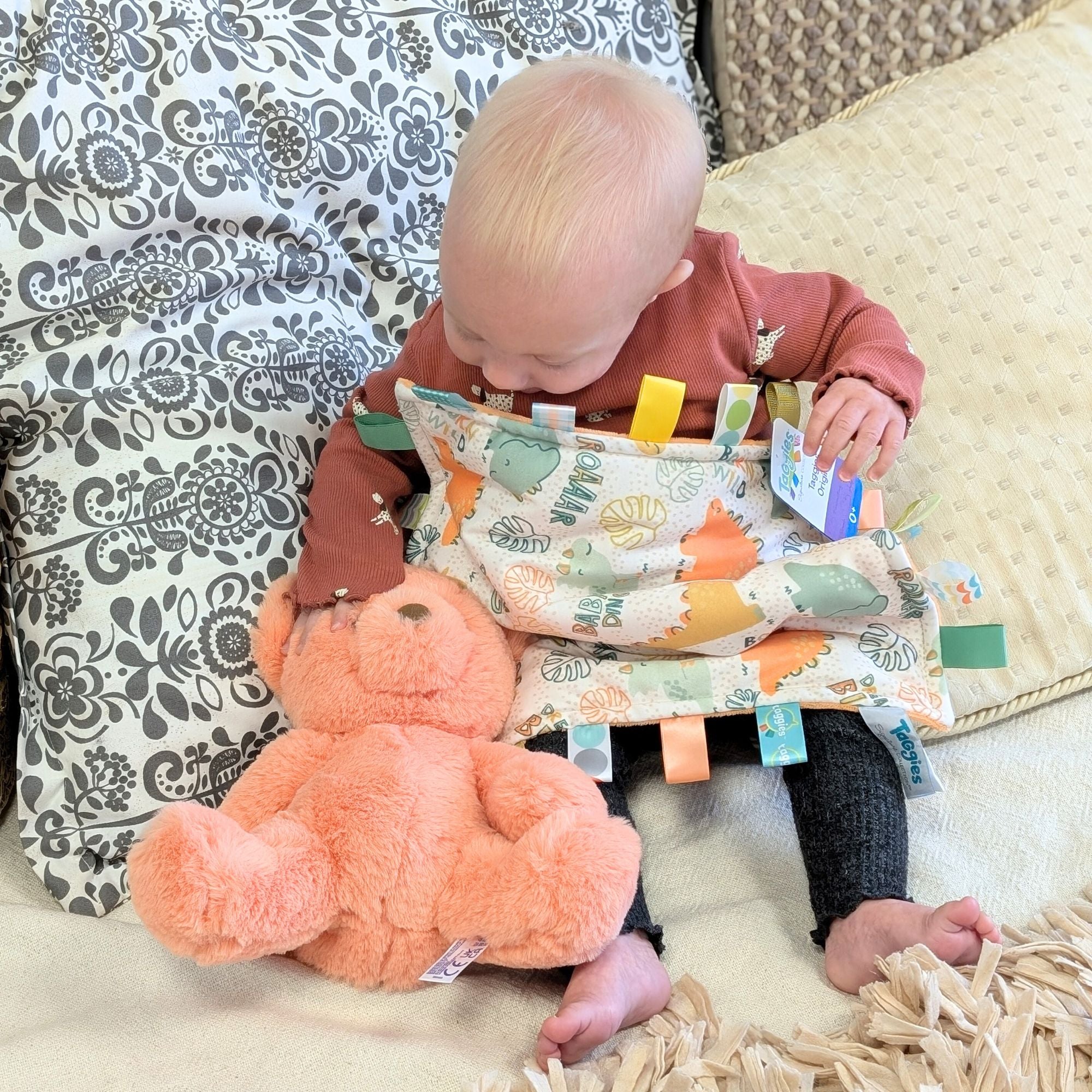 Baby with taggie toy and teddy.