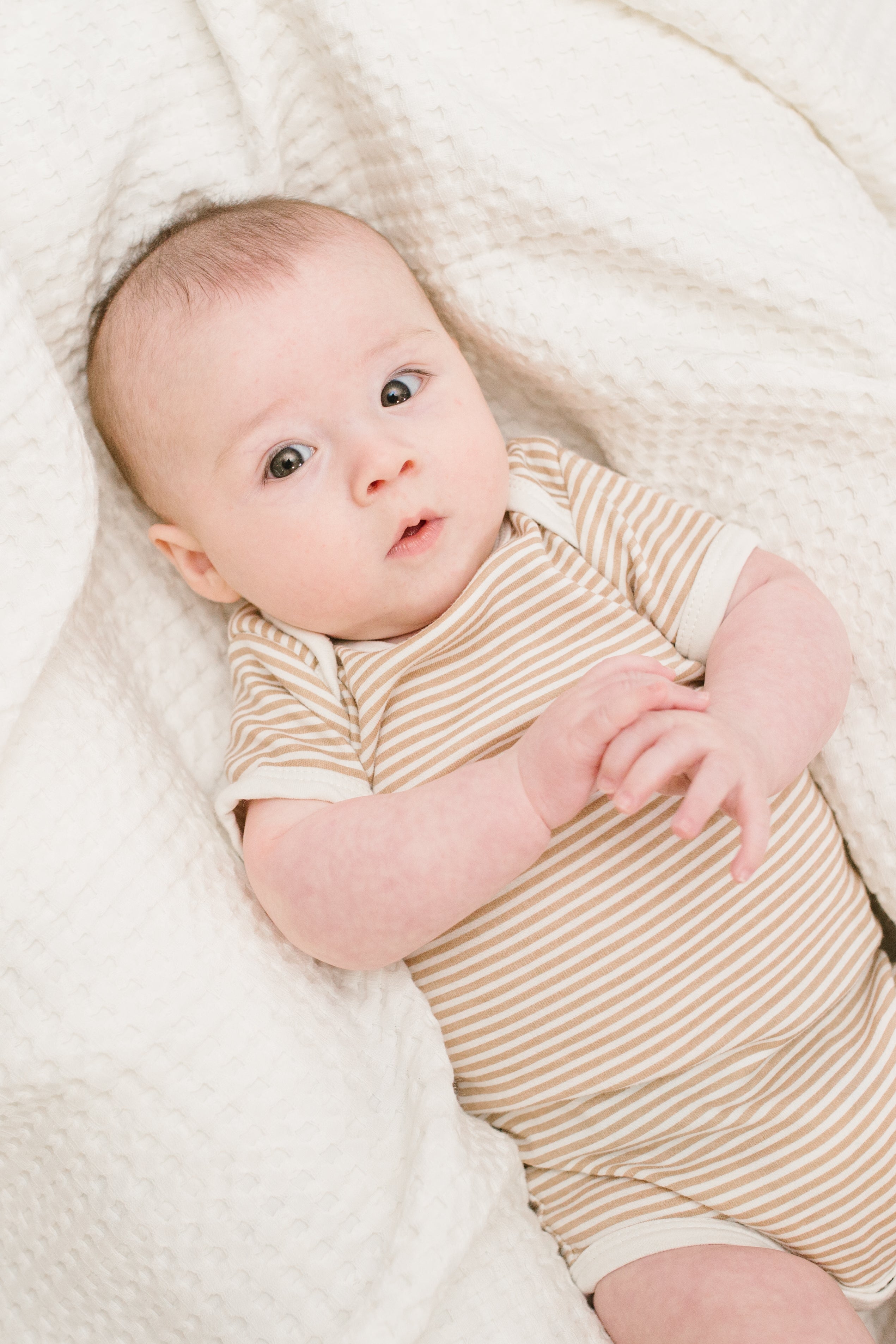 waffle baby blanket in cream, shown with baby.