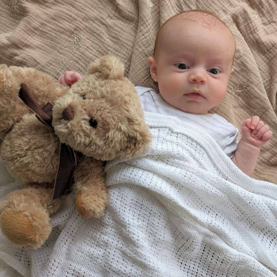 White baby cellular blanket covering a baby.