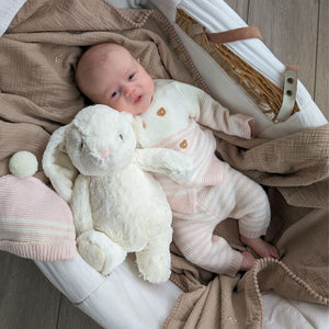 White dewey bunny soft toy and baby in moses basket.