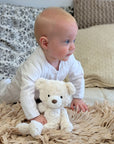 Baby crawling with a white teddy bear.