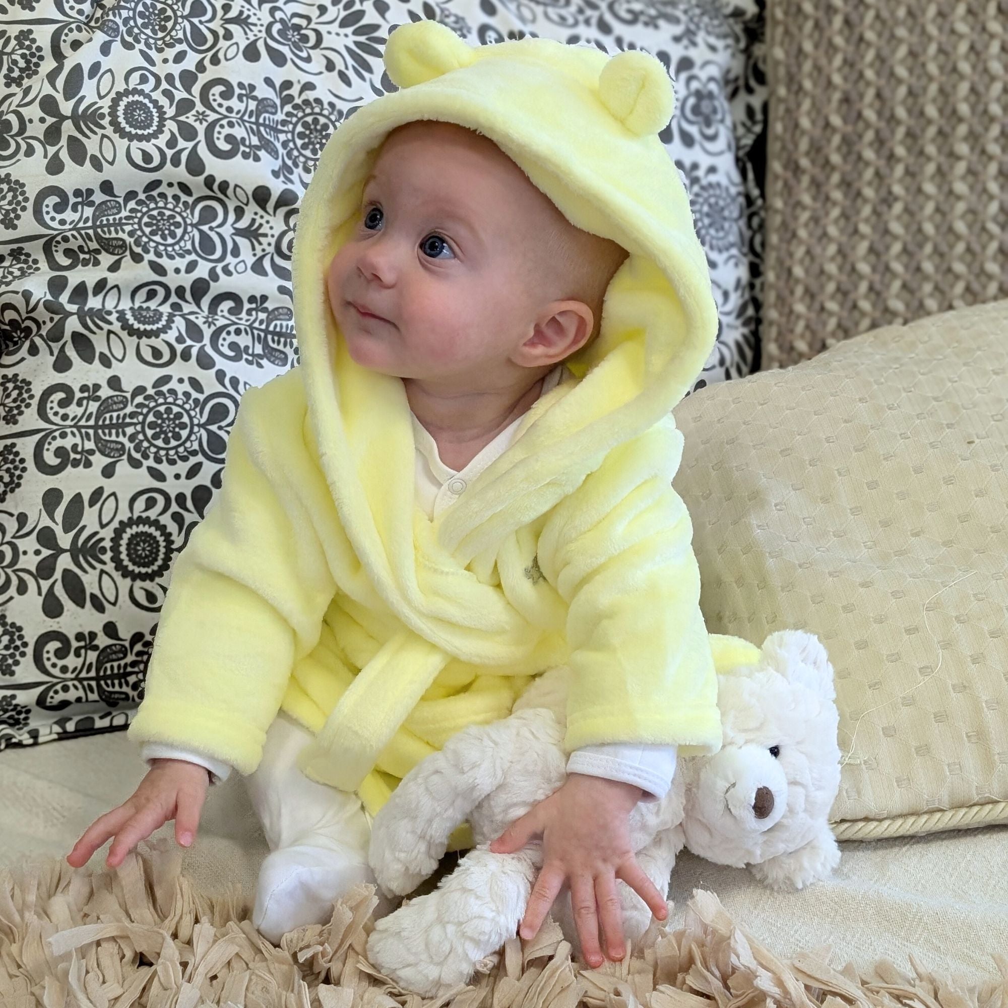 Yellow baby dressing gown with cute bear ears modelled by a baby.