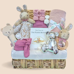 Baby girl hamper basket packed with gifts including flopsy bunny comforter and rattle. Also includes blanket and silver money box.