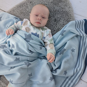 A soft blue blanket with blue stars knitted in.