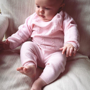 Baby wearing a pink knitted outfit.