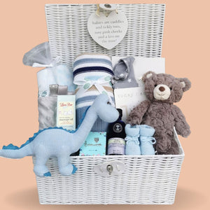 Large new baby boy gifts hamper with blue dinosaur, stripy blanket and teddy bear in a white hamper basket.